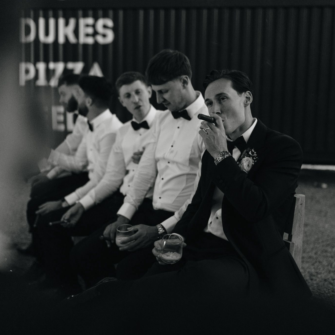 Groom in a black dinner jacket with groomsmen in black tie