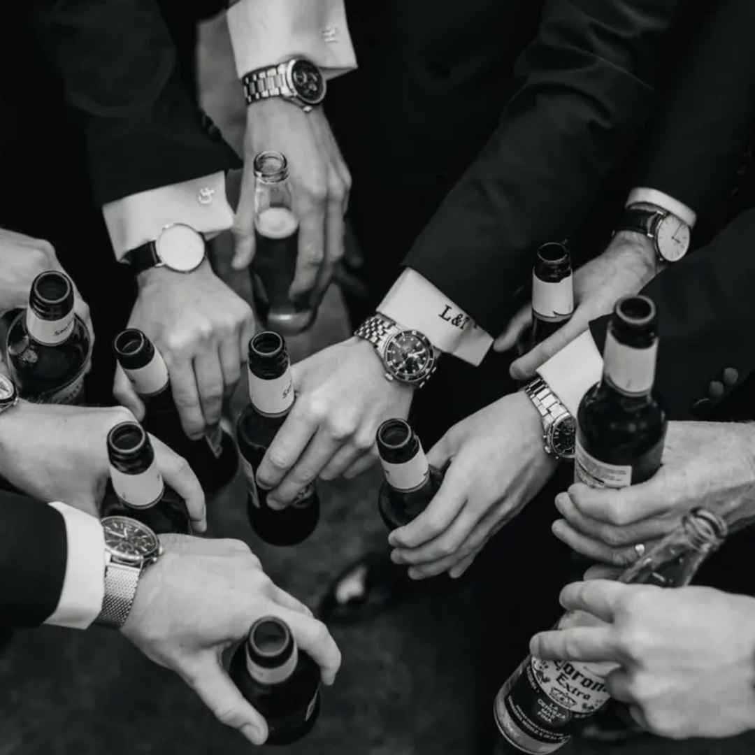 Groomsmen in tailored suits toasting with bottles